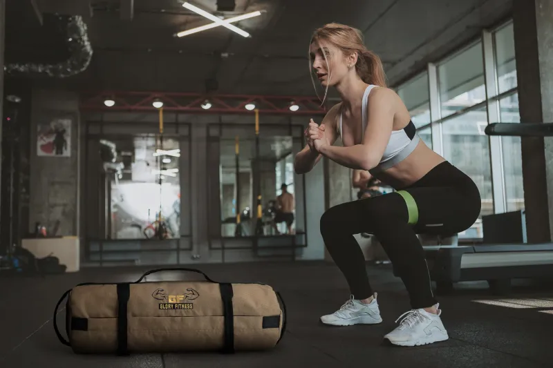 Glory Fitness workout sandbag with woman using a resistance band, lifestyle photography